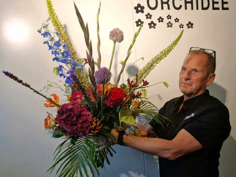 The owner of Bloemenhuis Orchidee with a large bouquet